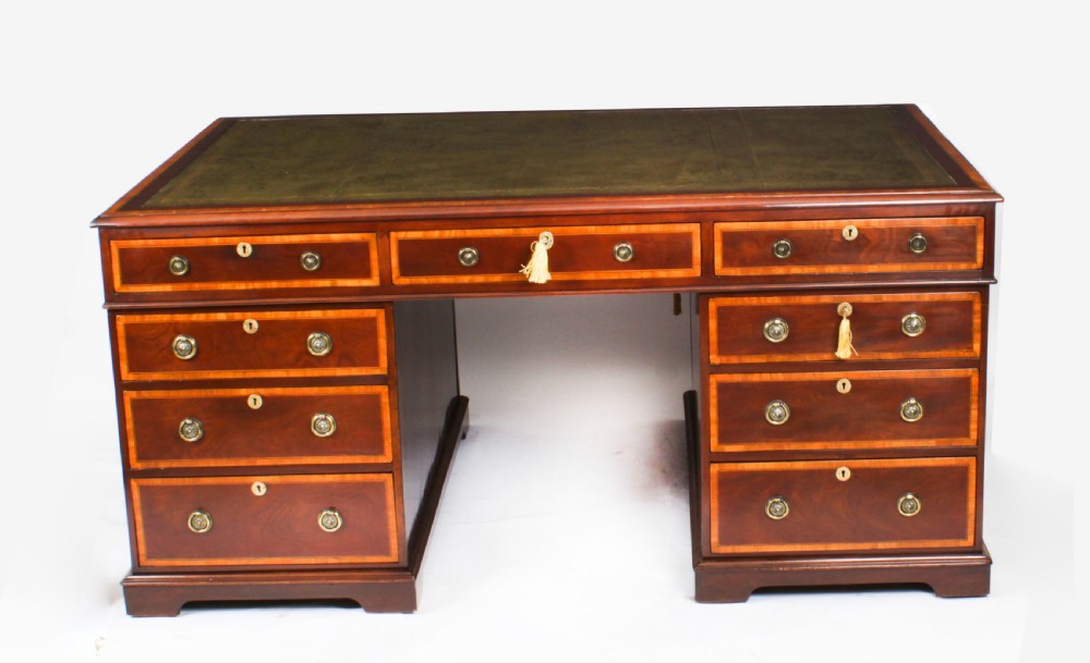 A Victorian flame mahogany partners pedestal desk featuring a green leather inset top and crossbanded drawer fronts with brass ring handles.