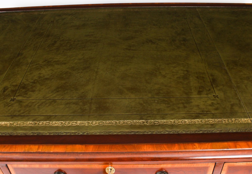 A Victorian flame mahogany partners pedestal desk featuring a green leather inset top and crossbanded drawer fronts with brass ring handles. View IV