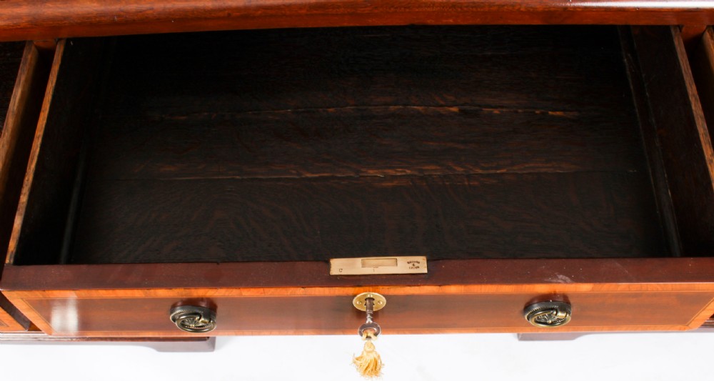 A Victorian flame mahogany partners pedestal desk featuring a green leather inset top and crossbanded drawer fronts with brass ring handles. View VII