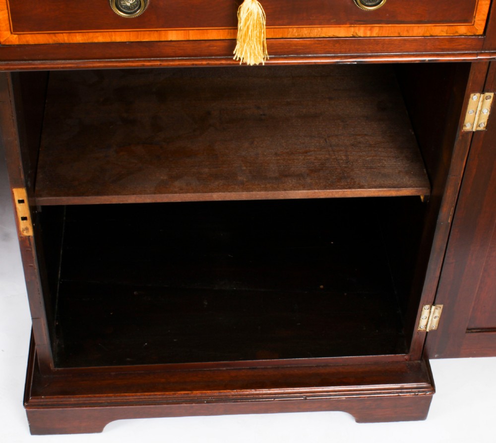A Victorian flame mahogany partners pedestal desk featuring a green leather inset top and crossbanded drawer fronts with brass ring handles. View XIV