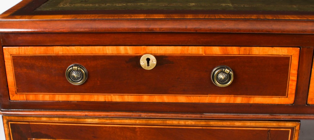 A Victorian flame mahogany partners pedestal desk featuring a green leather inset top and crossbanded drawer fronts with brass ring handles. View XV