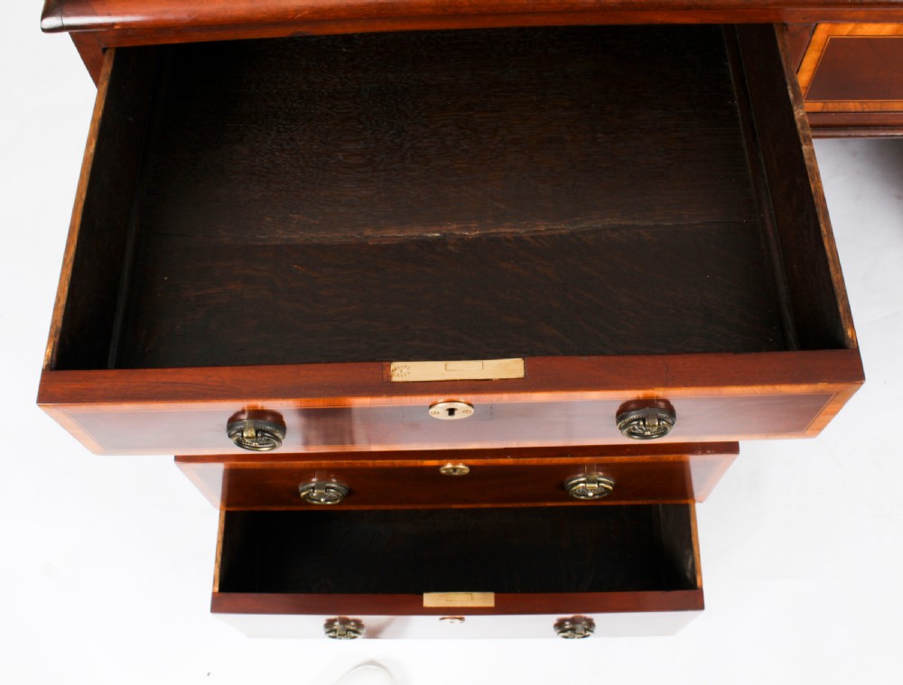 A Victorian flame mahogany partners pedestal desk featuring a green leather inset top and crossbanded drawer fronts with brass ring handles. View XXI