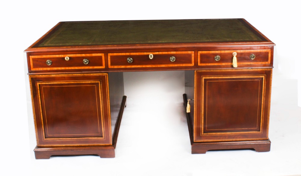 A Victorian flame mahogany partners pedestal desk featuring a green leather inset top and crossbanded drawer fronts with brass ring handles. View XXIII