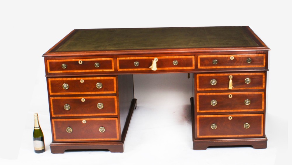 A Victorian flame mahogany partners pedestal desk featuring a green leather inset top and crossbanded drawer fronts with brass ring handles. View XXIV