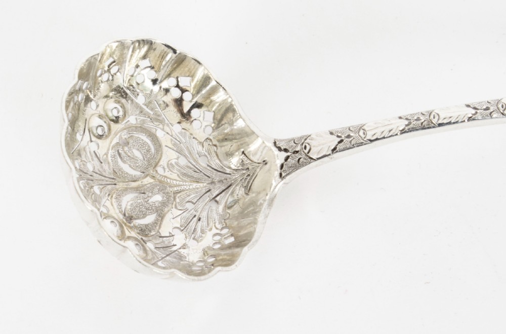 An open wooden case lined with deep purple velvet containing a silver-plated fruit serving set with embossed spoons and nutcrackers. View XV