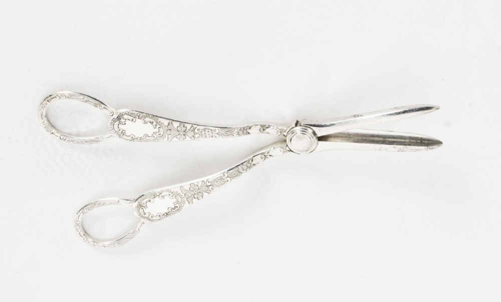 An open wooden case lined with deep purple velvet containing a silver-plated fruit serving set with embossed spoons and nutcrackers. View XXIII