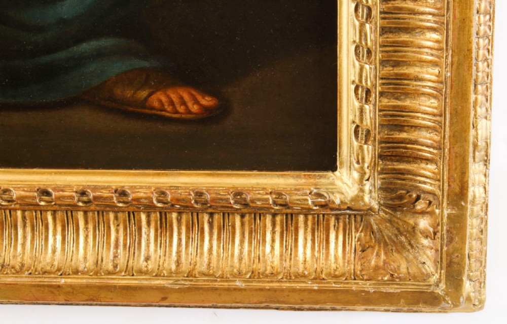 An oil painting depicting a seated young woman wearing a head turban and holding an illuminated scroll, encased in a fluted gold gilded frame. View X