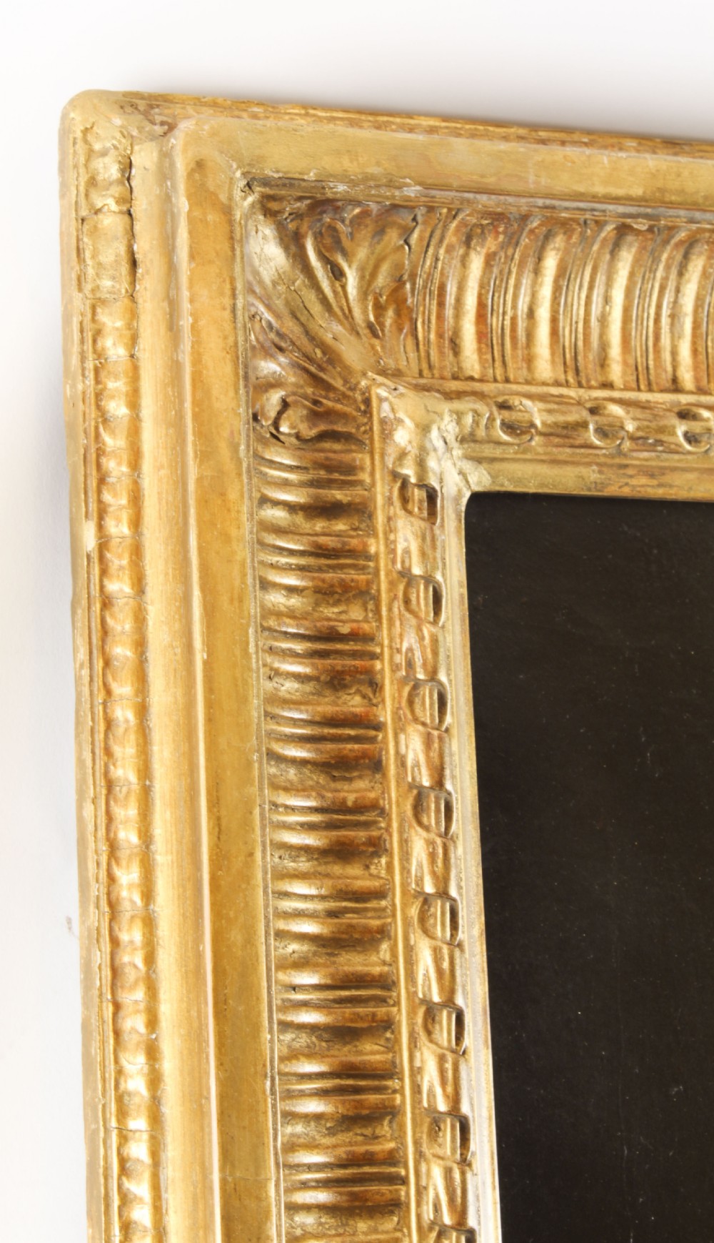 An oil painting depicting a seated young woman wearing a head turban and holding an illuminated scroll, encased in a fluted gold gilded frame. View XIV