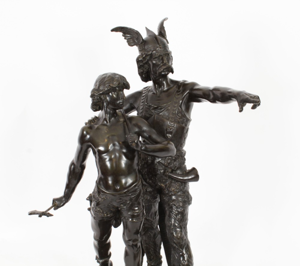 A 19th-century dark patinated bronze sculpture depicting a standing Gaulish warrior with a winged helmet pointing forward next to a young boy holding an axe on a rectangular base. View VII