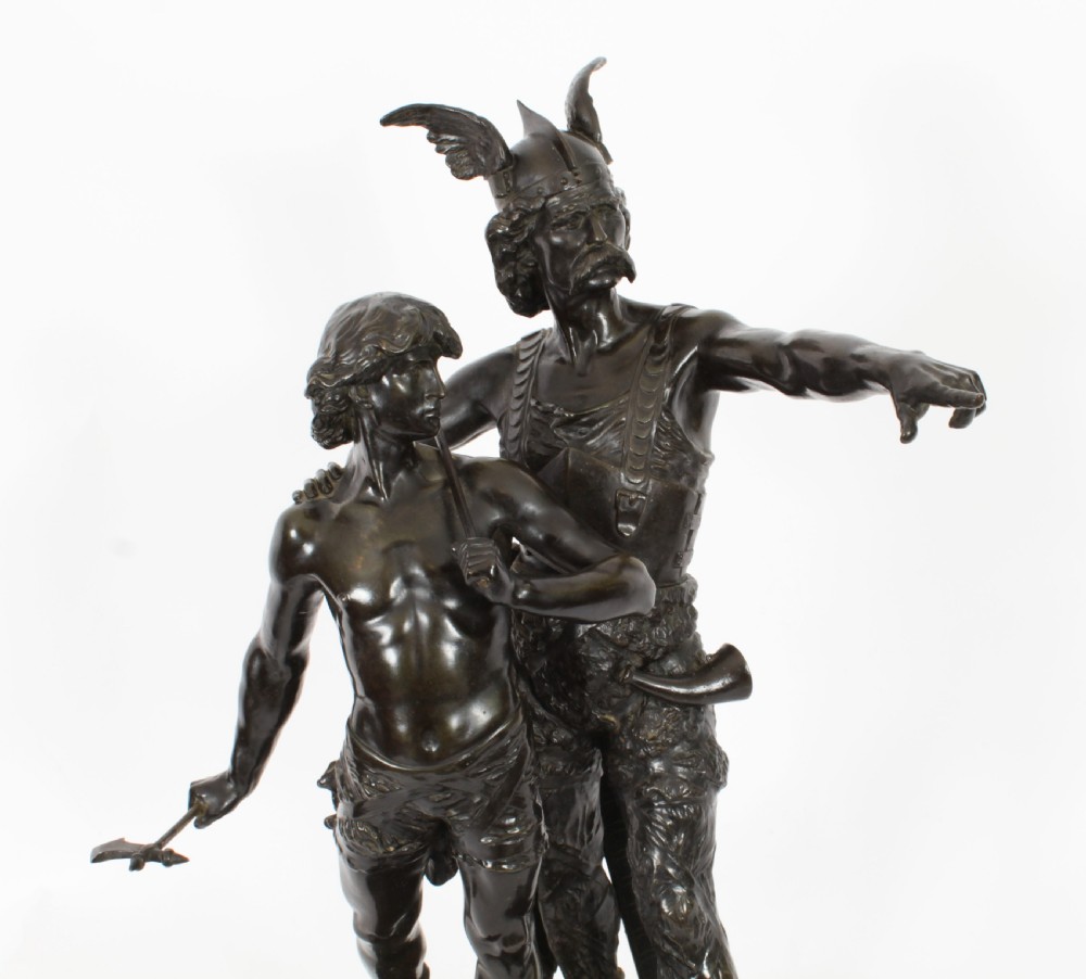 A 19th-century dark patinated bronze sculpture depicting a standing Gaulish warrior with a winged helmet pointing forward next to a young boy holding an axe on a rectangular base. View VIII