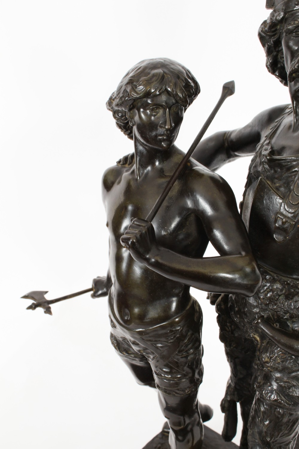 A 19th-century dark patinated bronze sculpture depicting a standing Gaulish warrior with a winged helmet pointing forward next to a young boy holding an axe on a rectangular base. View XI