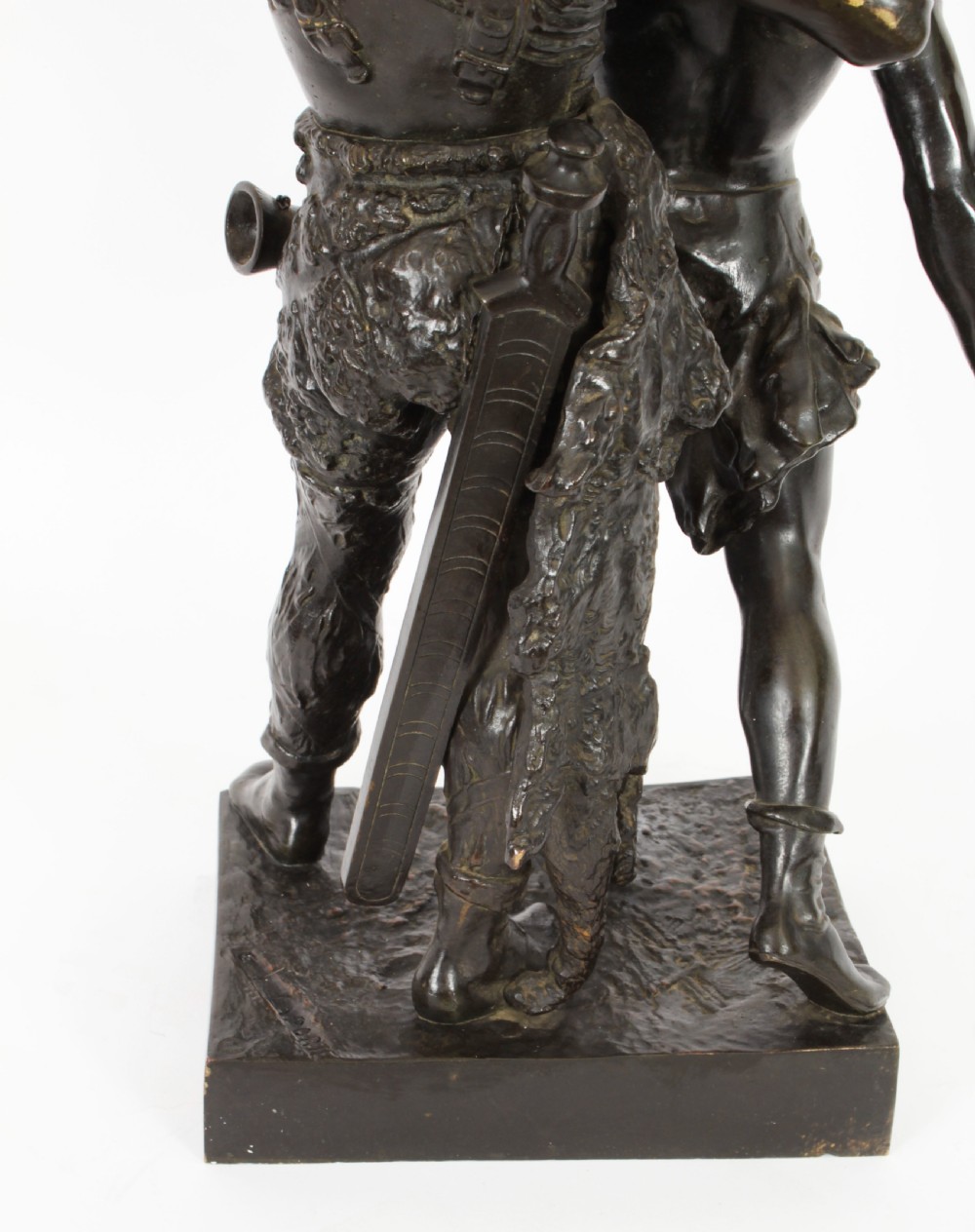 A 19th-century dark patinated bronze sculpture depicting a standing Gaulish warrior with a winged helmet pointing forward next to a young boy holding an axe on a rectangular base. View XIX