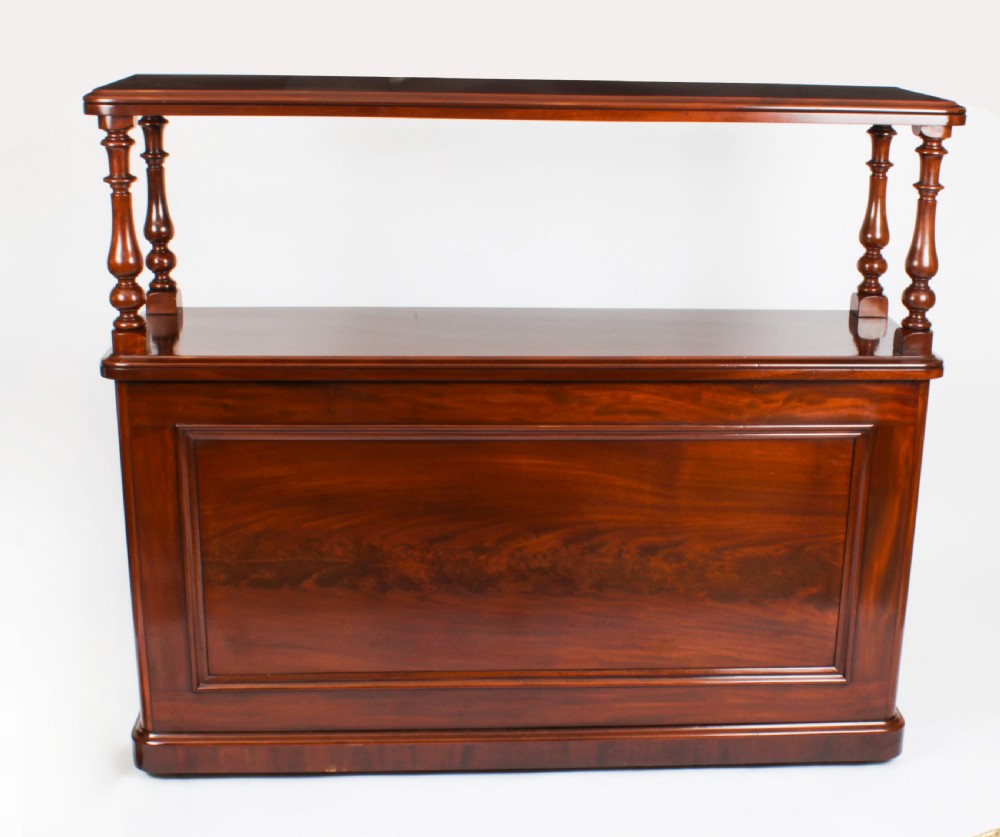 A Victorian flame mahogany dry bar featuring an elevated upper shelf supported by four turned balusters over a panelled lower counter. View II