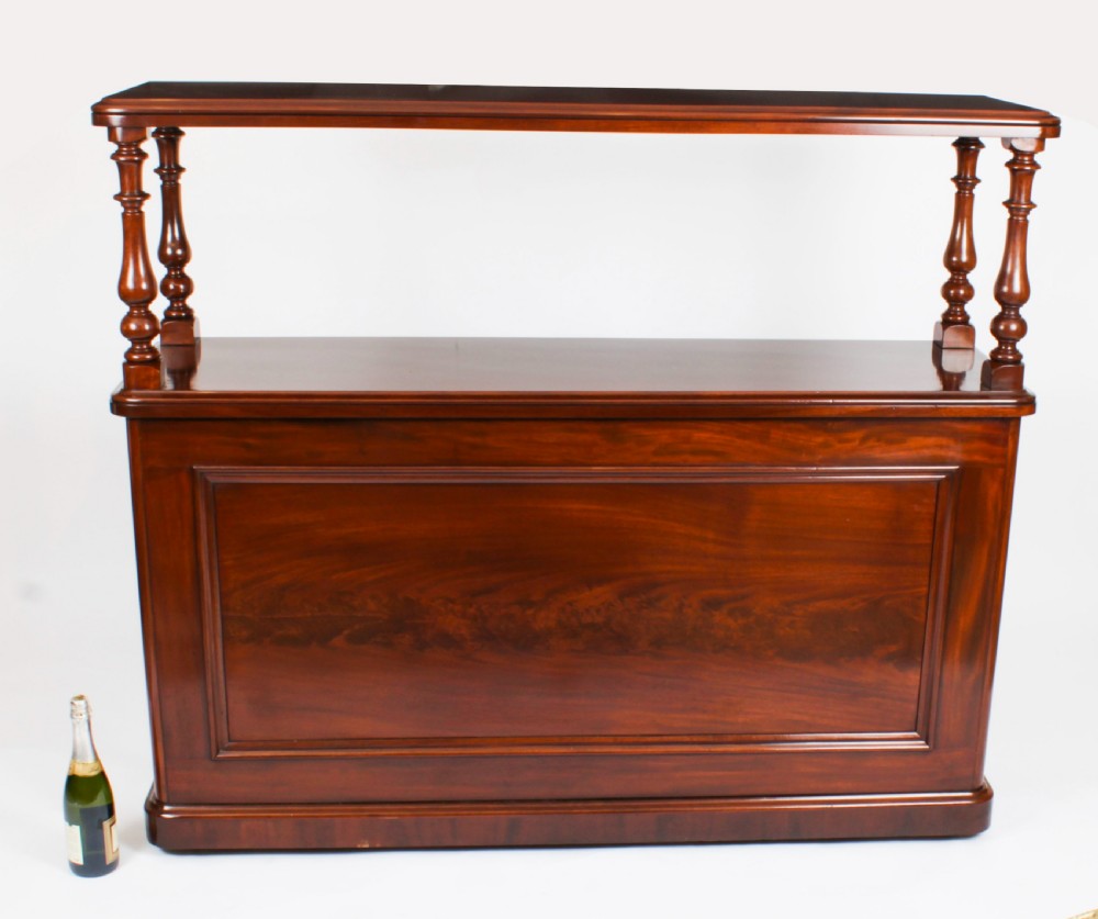 A Victorian flame mahogany dry bar featuring an elevated upper shelf supported by four turned balusters over a panelled lower counter. View XVII