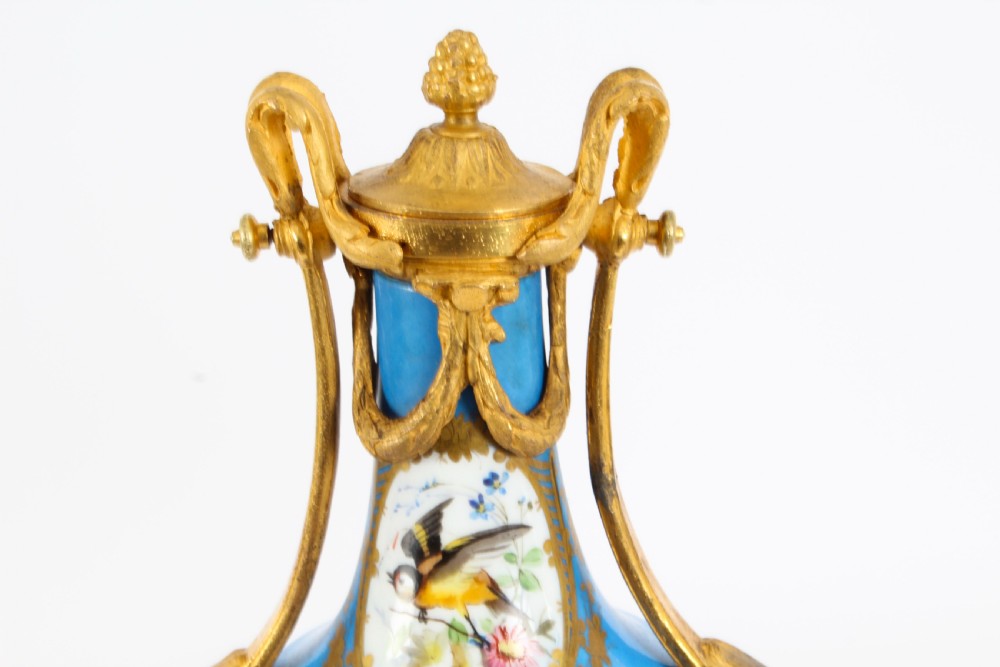 A pair of 19th-century French Sevres-style bleu celeste porcelain urns featuring hand-painted floral and bird reserves, supported by gilt metal mounts and pedestals. View V