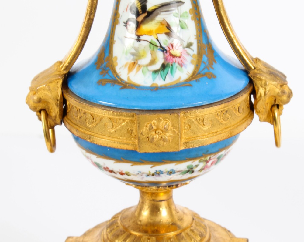 A pair of 19th-century French Sevres-style bleu celeste porcelain urns featuring hand-painted floral and bird reserves, supported by gilt metal mounts and pedestals. View VI