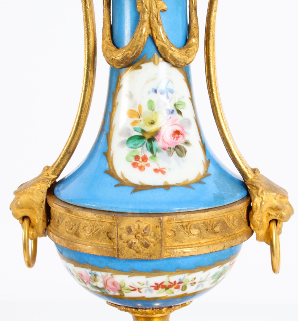 A pair of 19th-century French Sevres-style bleu celeste porcelain urns featuring hand-painted floral and bird reserves, supported by gilt metal mounts and pedestals. View XVII