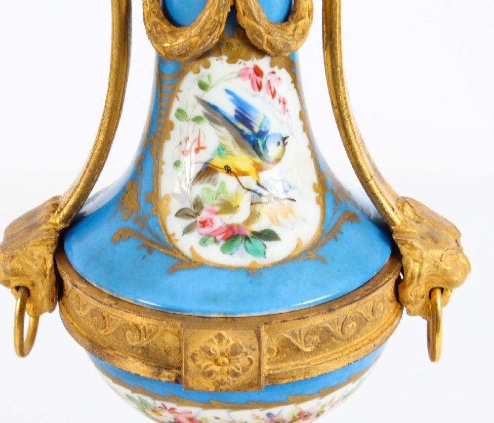 A pair of 19th-century French Sevres-style bleu celeste porcelain urns featuring hand-painted floral and bird reserves, supported by gilt metal mounts and pedestals. View XXI