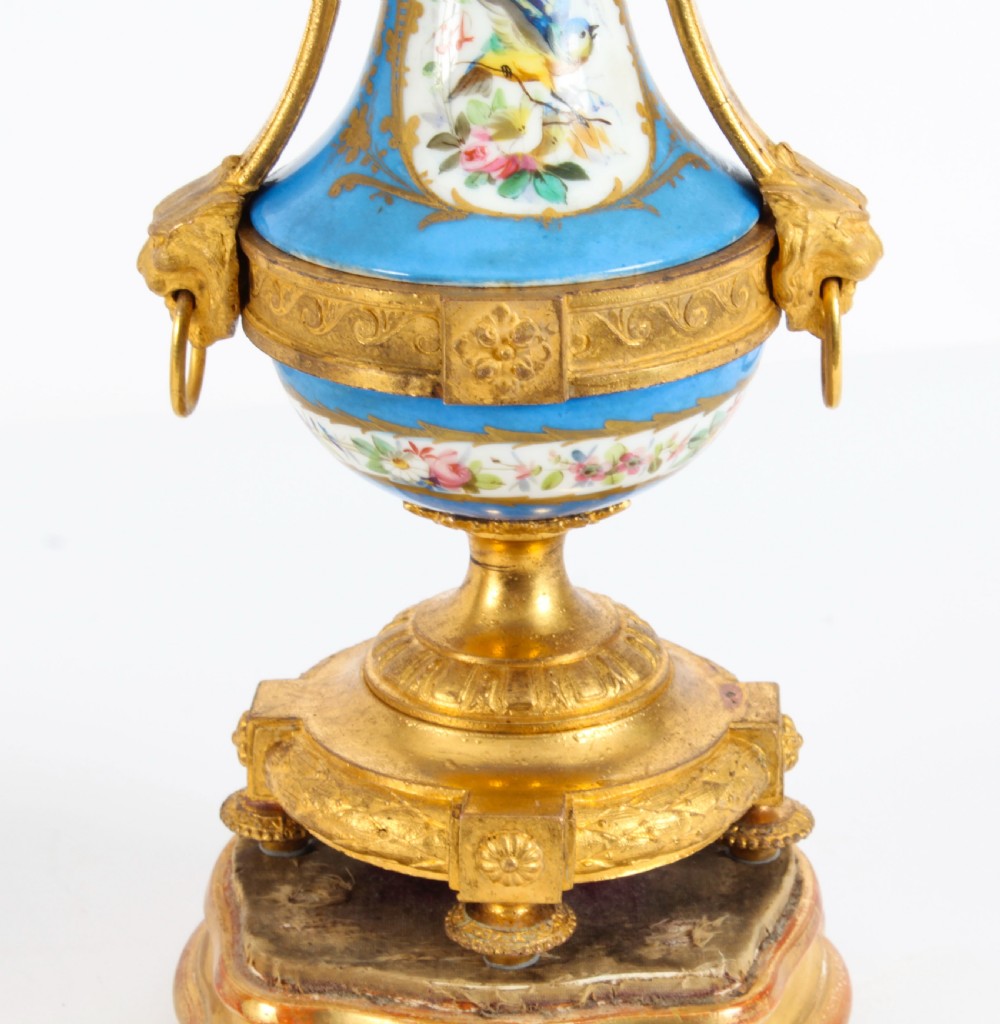 A pair of 19th-century French Sevres-style bleu celeste porcelain urns featuring hand-painted floral and bird reserves, supported by gilt metal mounts and pedestals. View XXII