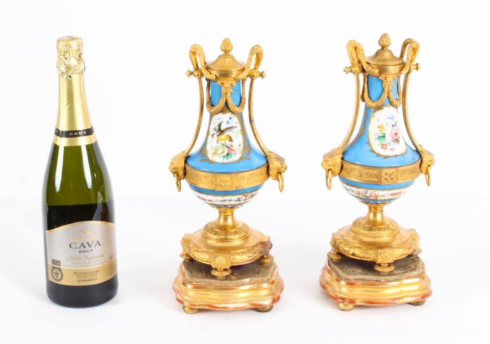 A pair of 19th-century French Sevres-style bleu celeste porcelain urns featuring hand-painted floral and bird reserves, supported by gilt metal mounts and pedestals. View XXIII