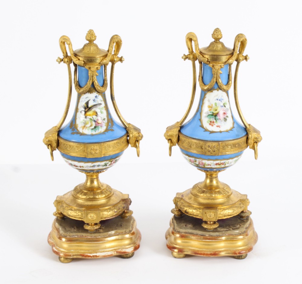 A pair of 19th-century French Sevres-style bleu celeste porcelain urns featuring hand-painted floral and bird reserves, supported by gilt metal mounts and pedestals. View XXIV
