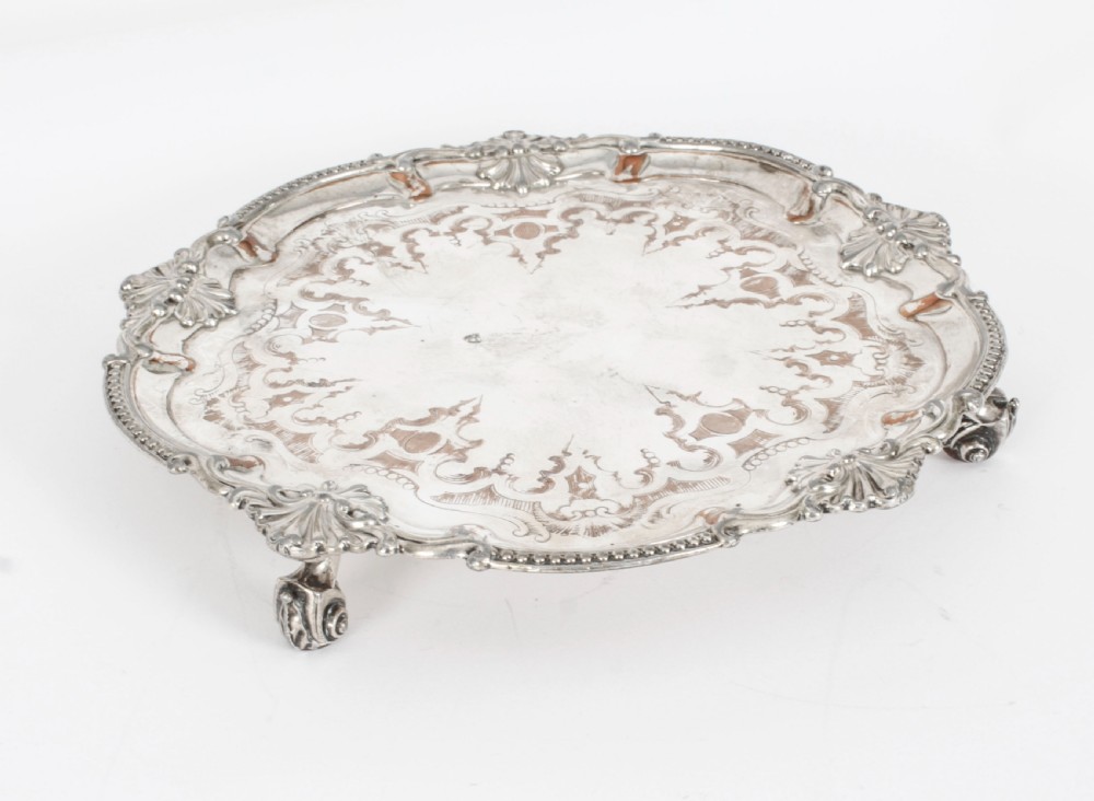 A Georgian Old Sheffield plate silver-plated salver featuring chased scroll engravings, shell motifs on a beaded rim, and resting on short feet. View II