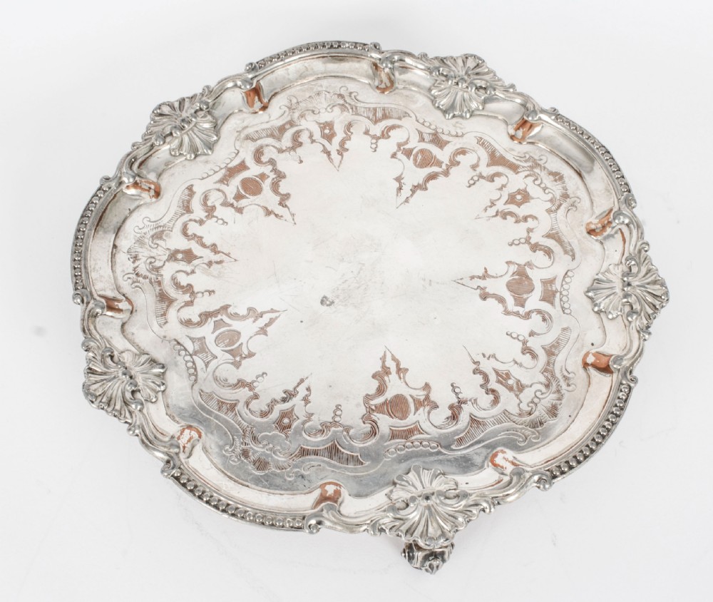 A Georgian Old Sheffield plate silver-plated salver featuring chased scroll engravings, shell motifs on a beaded rim, and resting on short feet. View IV