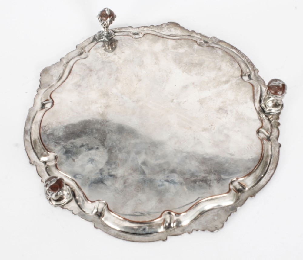 A Georgian Old Sheffield plate silver-plated salver featuring chased scroll engravings, shell motifs on a beaded rim, and resting on short feet. View X