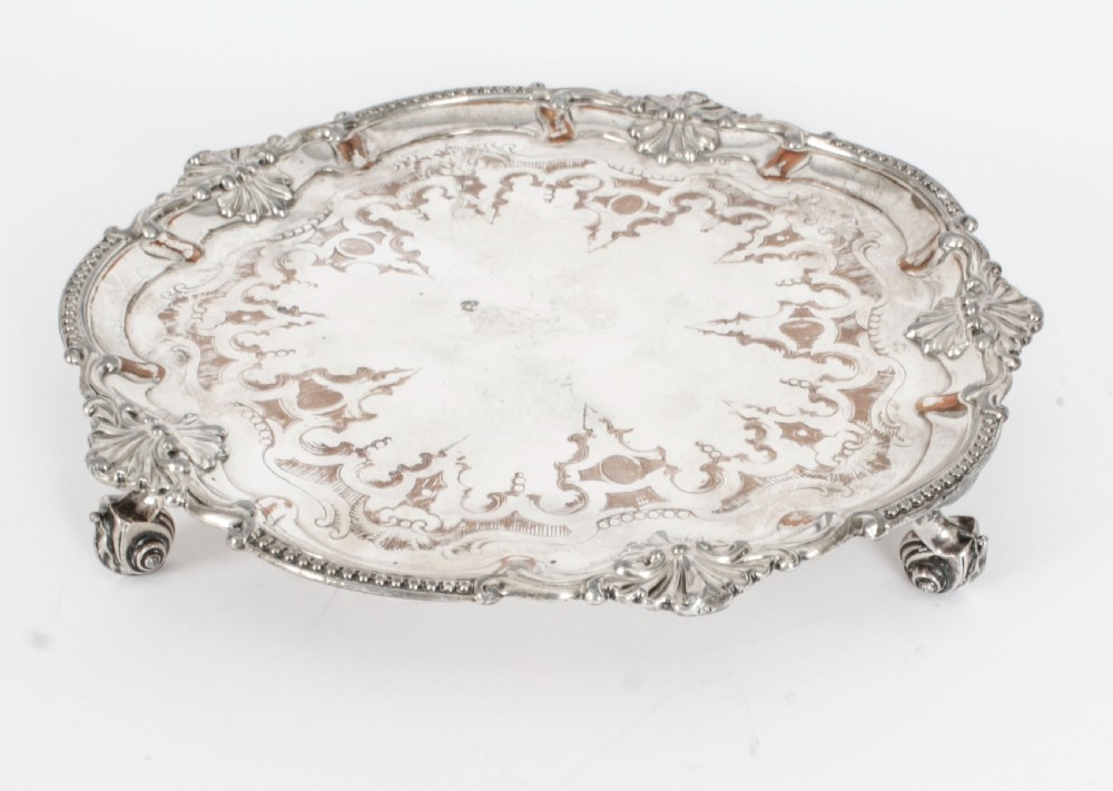 A Georgian Old Sheffield plate silver-plated salver featuring chased scroll engravings, shell motifs on a beaded rim, and resting on short feet. View XII