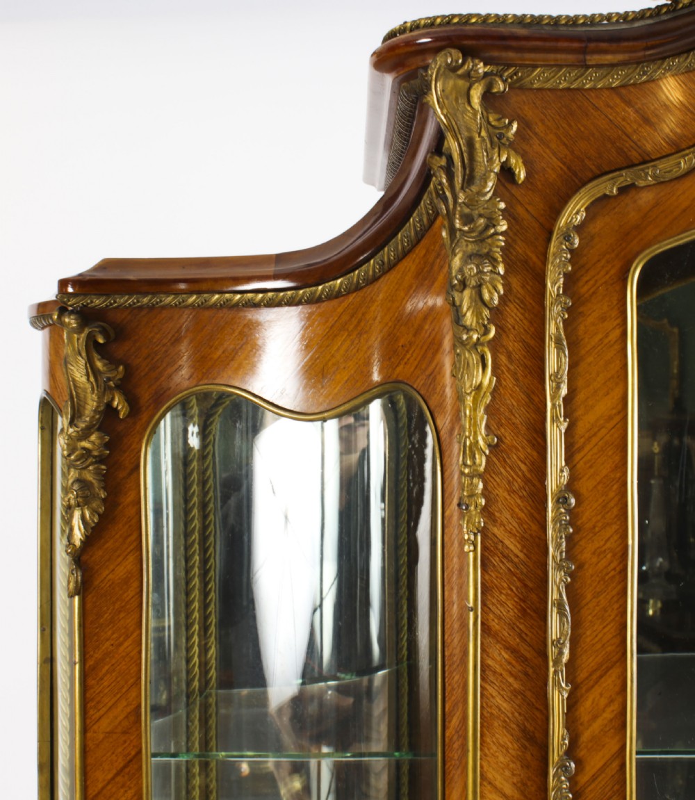 A nineteenth-century French Louis XV style bombee vitrine cabinet featuring curved glass panels, hand-painted Vernis Martin lower sections, and ornate gilt bronze mounts. View V