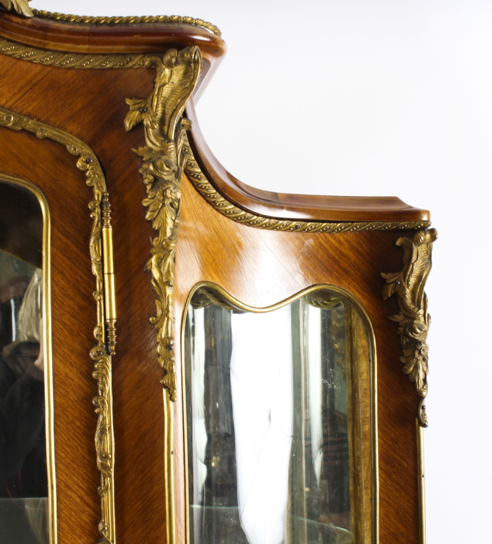 A nineteenth-century French Louis XV style bombee vitrine cabinet featuring curved glass panels, hand-painted Vernis Martin lower sections, and ornate gilt bronze mounts. View VI