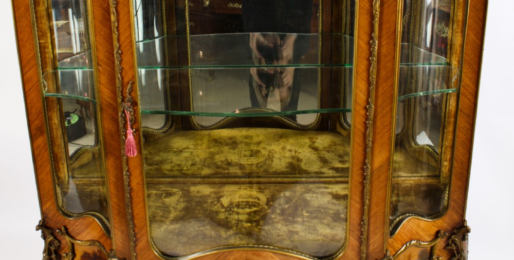 A nineteenth-century French Louis XV style bombee vitrine cabinet featuring curved glass panels, hand-painted Vernis Martin lower sections, and ornate gilt bronze mounts. View VII