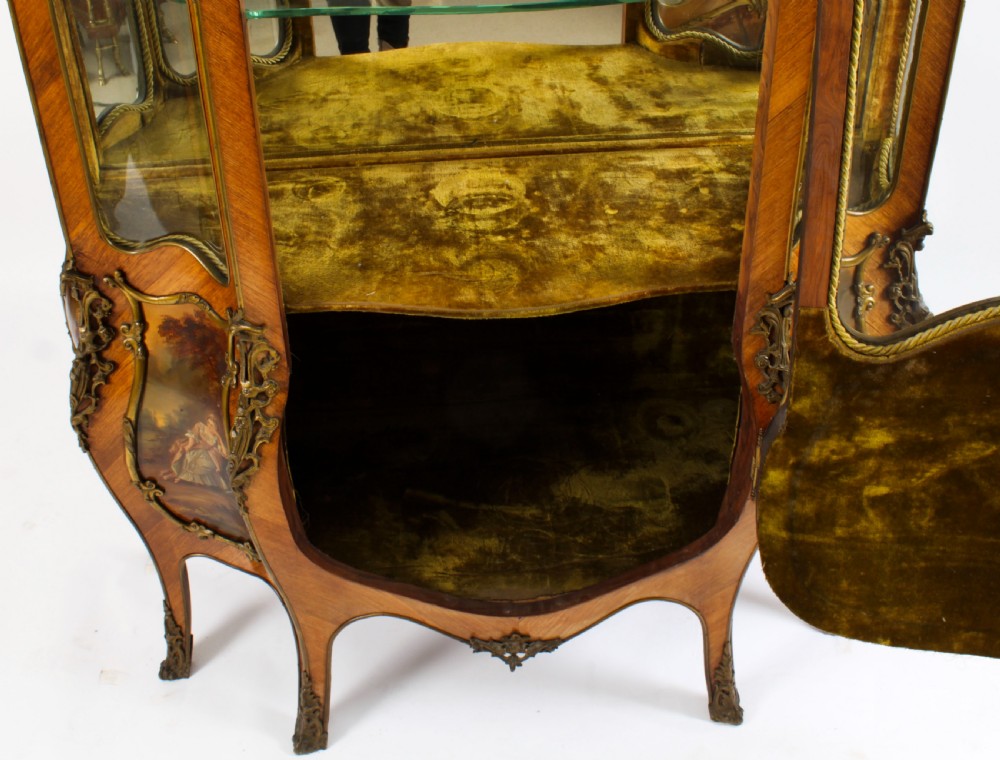A nineteenth-century French Louis XV style bombee vitrine cabinet featuring curved glass panels, hand-painted Vernis Martin lower sections, and ornate gilt bronze mounts. View XIX