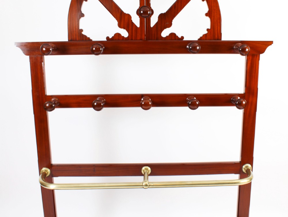 A Victorian mahogany hall stand featuring an arched fretwork top with wooden peg hooks, a brass umbrella bar, and a fitted drip pan base. View VII