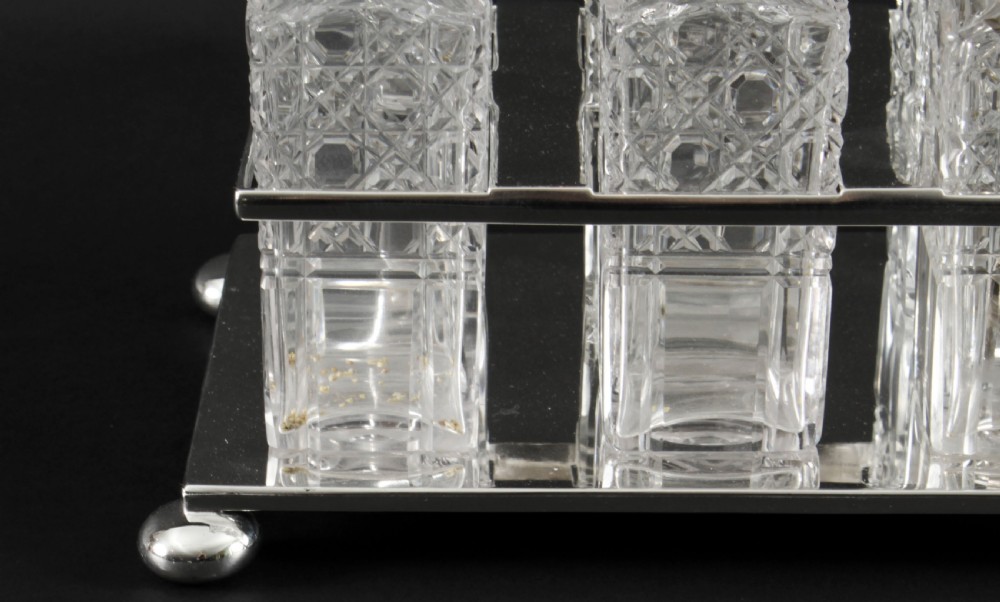 A Victorian silver-plated rectangular cruet stand holding six faceted cut-glass condiment bottles with metal tops and glass stoppers. View IV