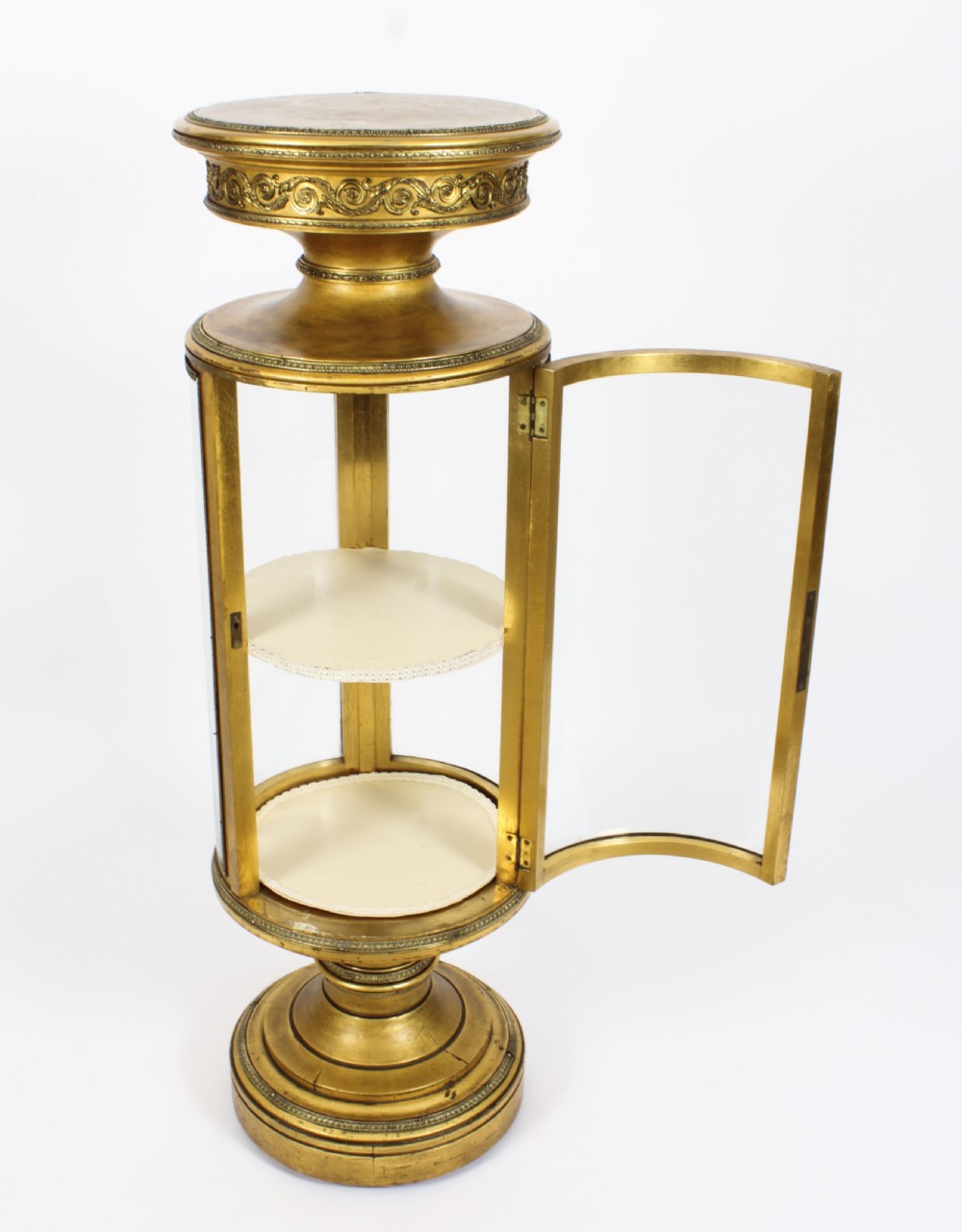 A 19th-century French giltwood cylindrical pedestal display cabinet featuring curved glass panels, an interior shelf, and carved guilloche mouldings. View XII