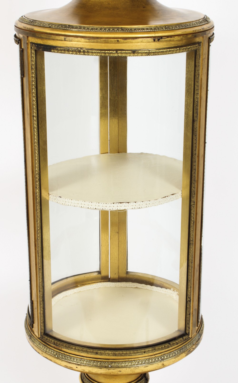 A 19th-century French giltwood cylindrical pedestal display cabinet featuring curved glass panels, an interior shelf, and carved guilloche mouldings. View XIII