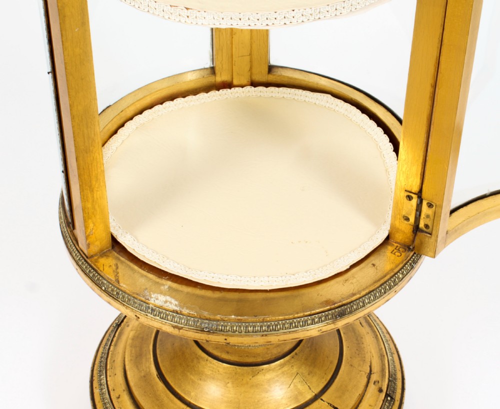 A 19th-century French giltwood cylindrical pedestal display cabinet featuring curved glass panels, an interior shelf, and carved guilloche mouldings. View XVII