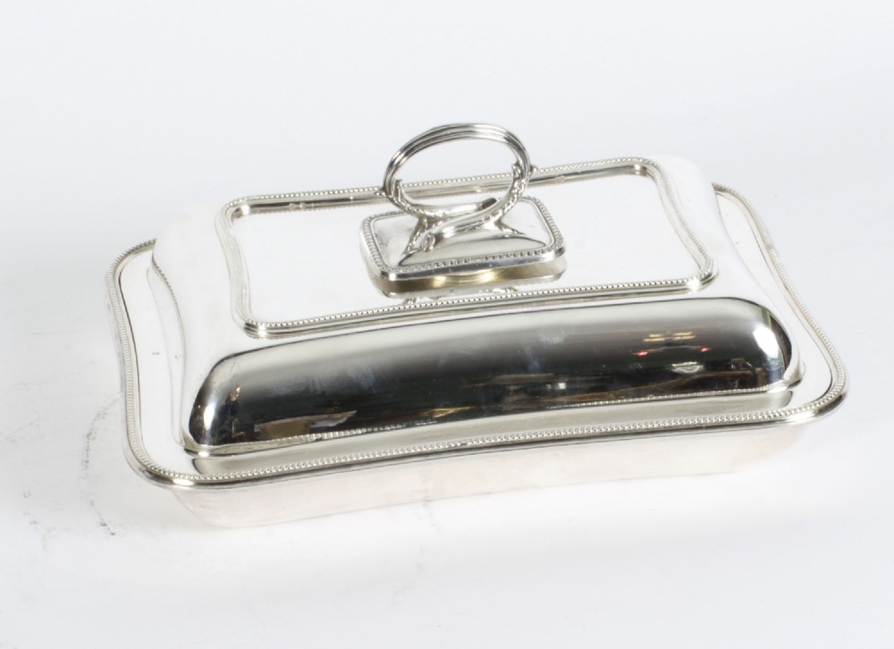 A rectangular antique silver-plated entree dish featuring a fitted lid with a loop handle and fine beaded border details.