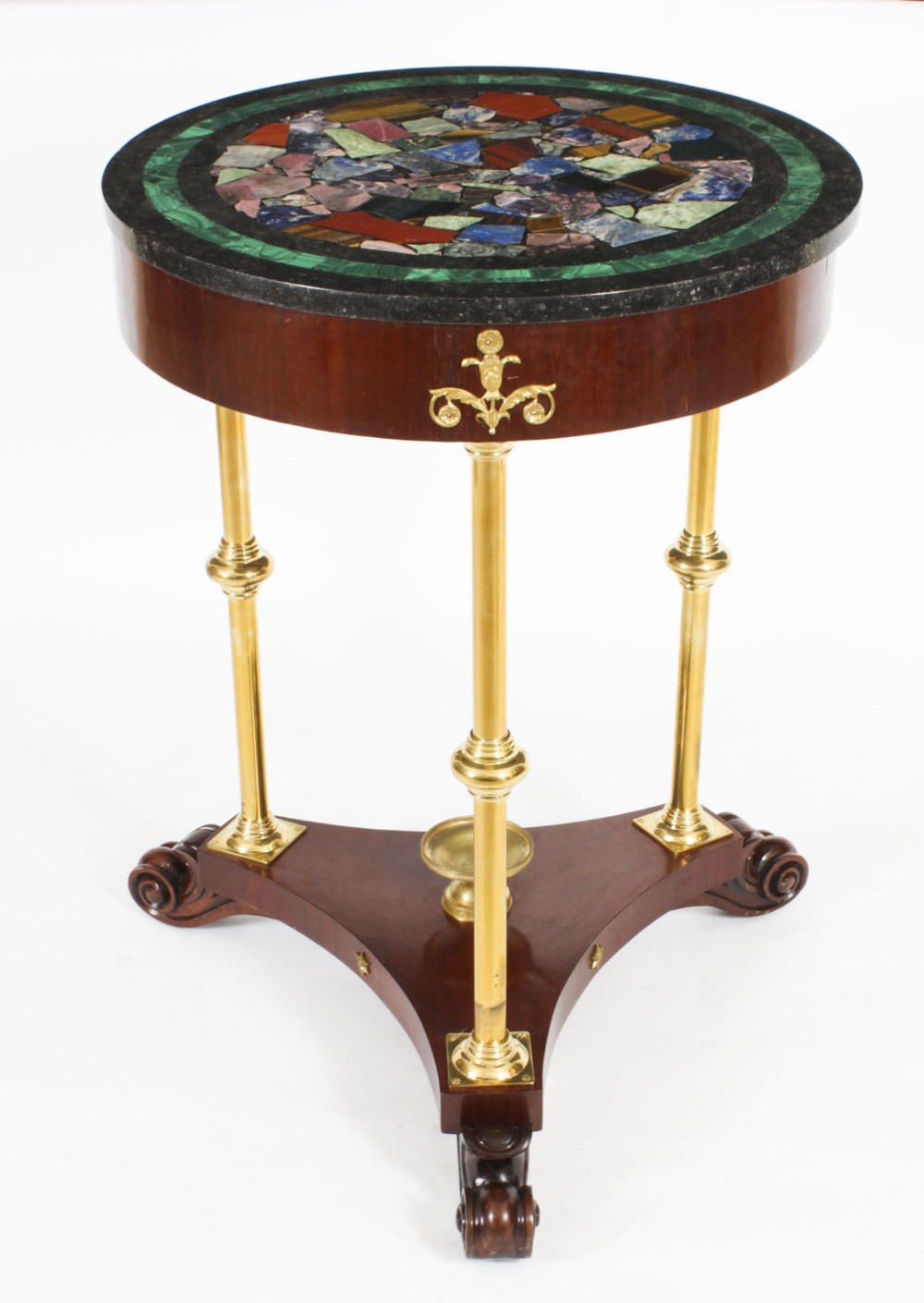 A circular early 20th-century Italian occasional table featuring a colourful pietra dura inlaid stone top supported by three brass columns on a mahogany triform base.