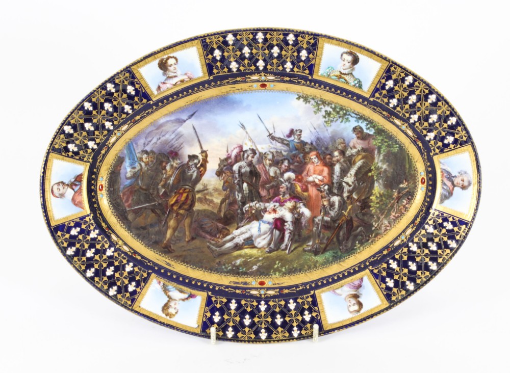 An antique French oval porcelain dish featuring a central hand-painted historical battle scene surrounded by a cobalt blue border with gilt lattice work and portrait cartouches.