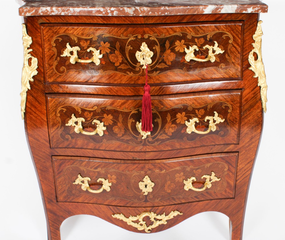 A 19th-century French Louis XV Revival commode with floral marquetry inlay, a variegated marble top, three drawers, and gilt-bronze mounts. View VI