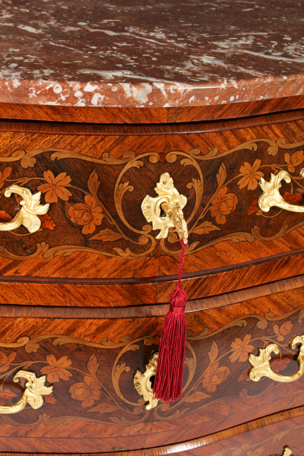 A 19th-century French Louis XV Revival commode with floral marquetry inlay, a variegated marble top, three drawers, and gilt-bronze mounts. View IX