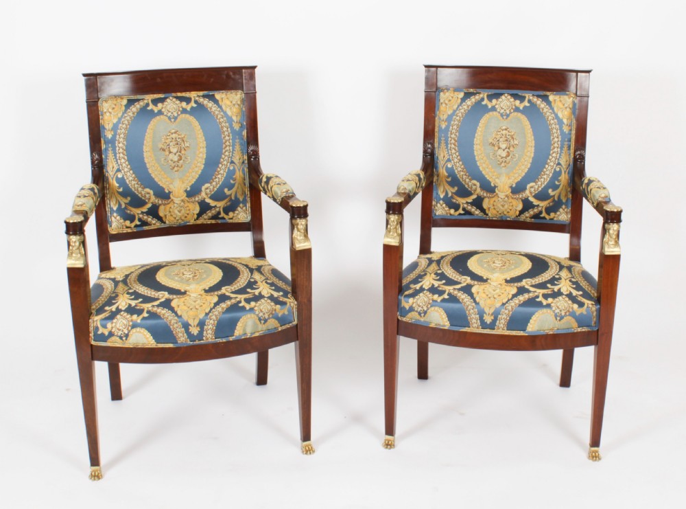 A pair of 19th-century French Empire Revival mahogany armchairs upholstered in blue and gold patterned silk damask featuring gilt ormolu mounts.