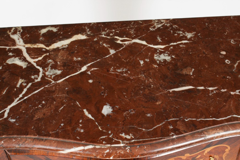 A French Louis XV Revival style marquetry commode featuring floral timber inlays, gilt-bronze mounts, three drawers, and a contoured marble top. View IV