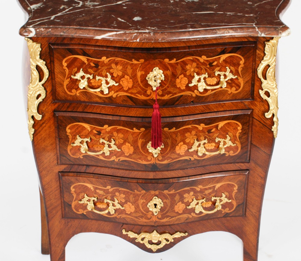 A French Louis XV Revival style marquetry commode featuring floral timber inlays, gilt-bronze mounts, three drawers, and a contoured marble top. View V