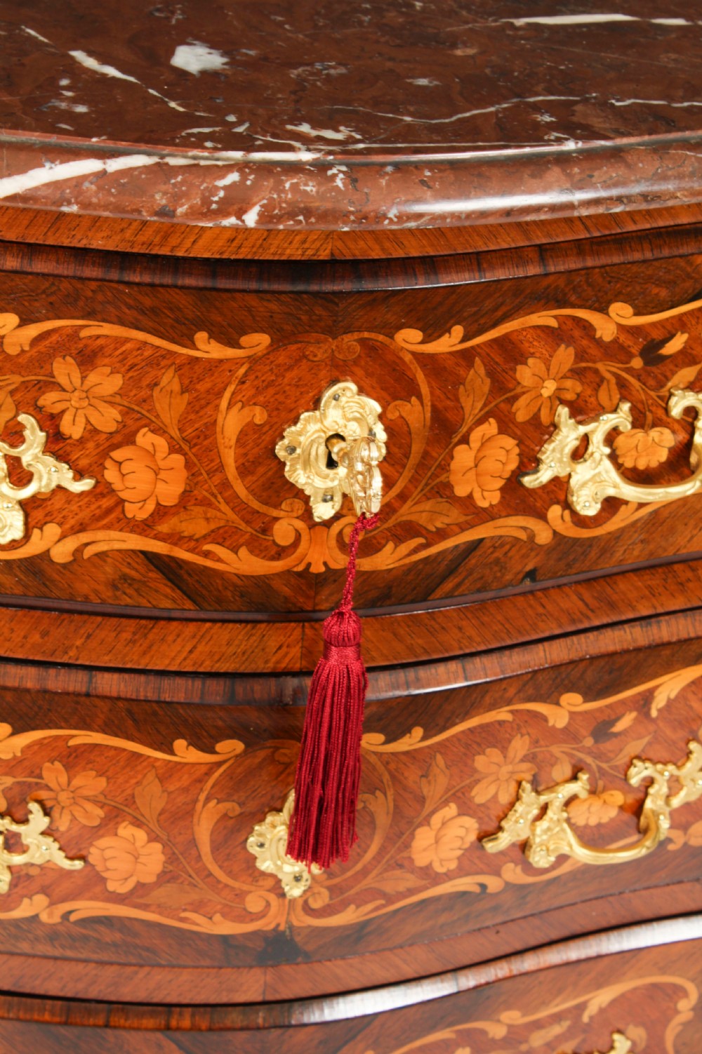 A French Louis XV Revival style marquetry commode featuring floral timber inlays, gilt-bronze mounts, three drawers, and a contoured marble top. View VIII