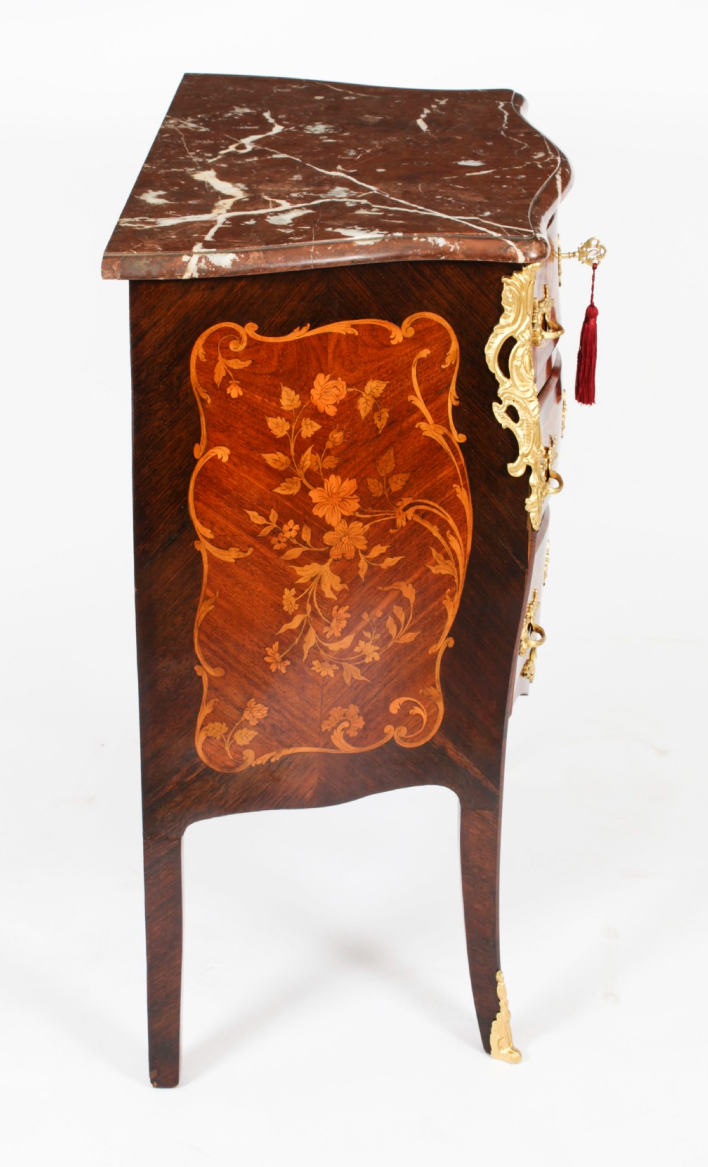 A French Louis XV Revival style marquetry commode featuring floral timber inlays, gilt-bronze mounts, three drawers, and a contoured marble top. View XVIII