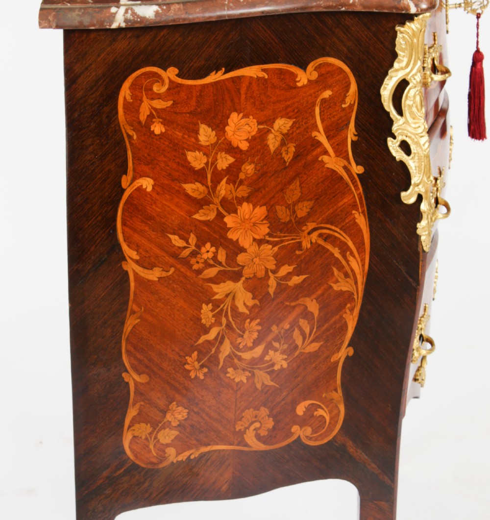 A French Louis XV Revival style marquetry commode featuring floral timber inlays, gilt-bronze mounts, three drawers, and a contoured marble top. View XIX
