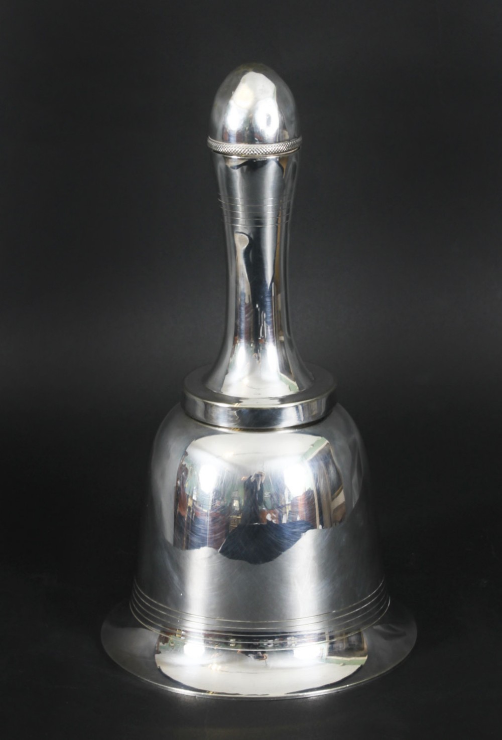A silver-plated Art Deco cocktail shaker shaped like a handbell with a polished metal finish.